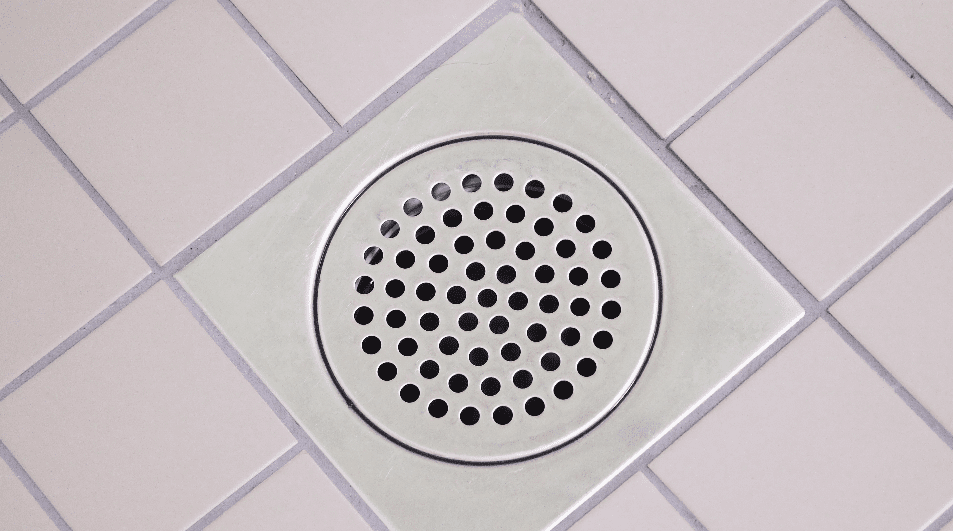 Shower floor after fixing a clogged shower drain, previously clogged with buildup and standing water.