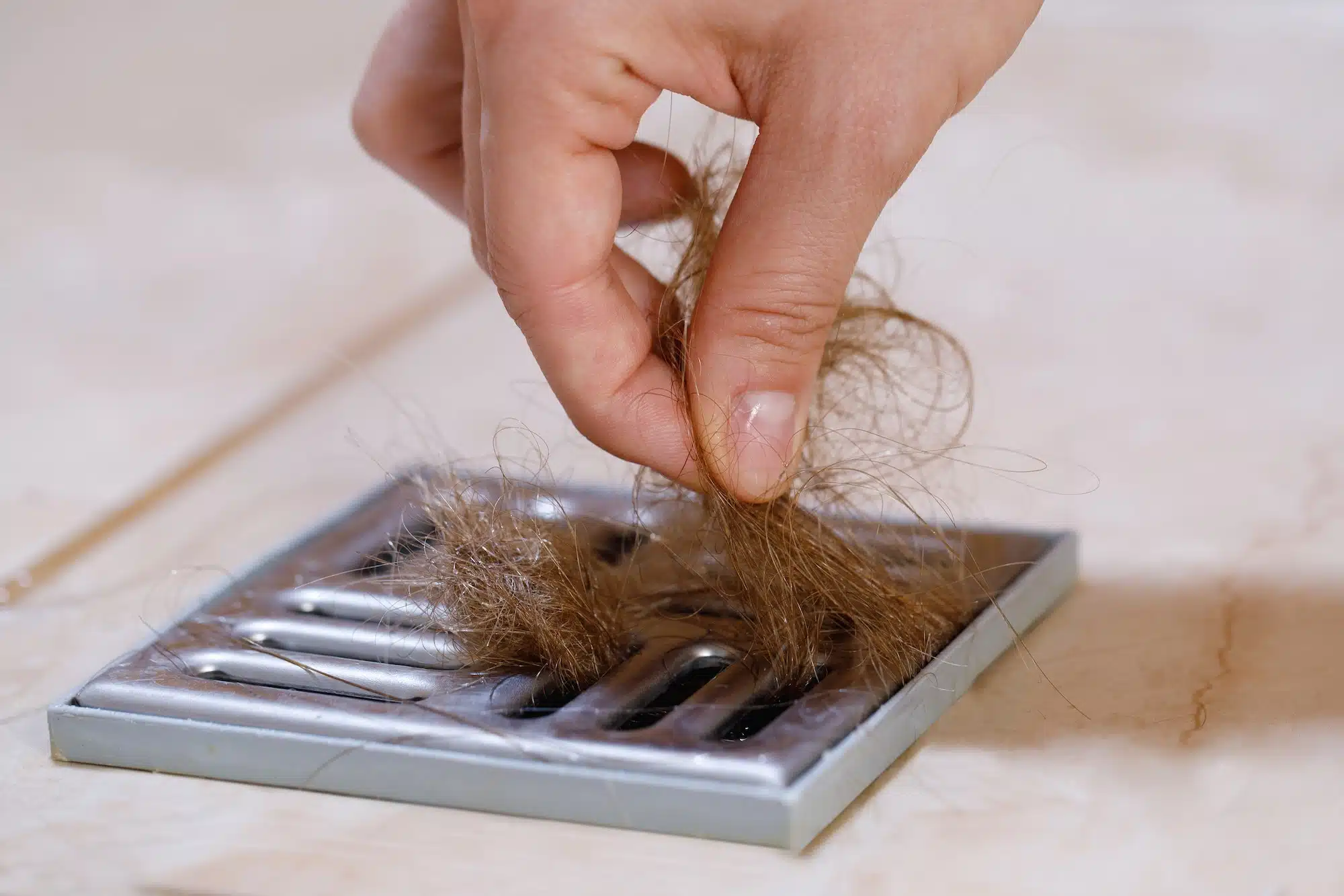 Woman removing hair clump from the shower drain